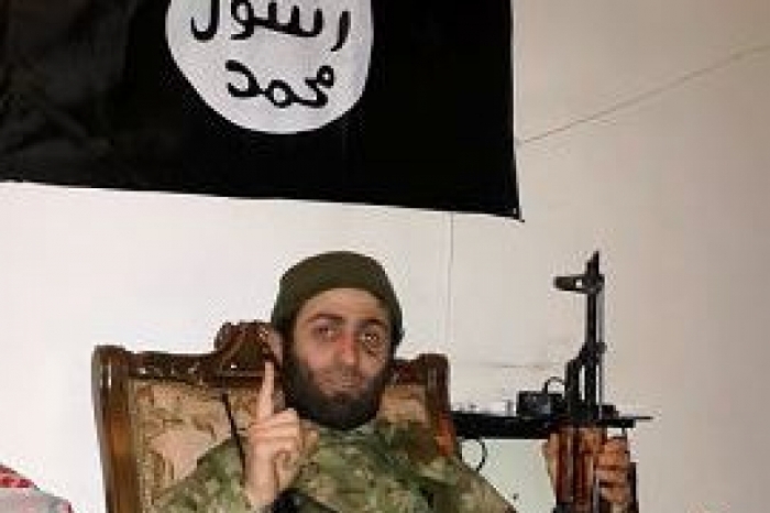 Chaghadildze holds an AK47 while posing under the ISIS flag.